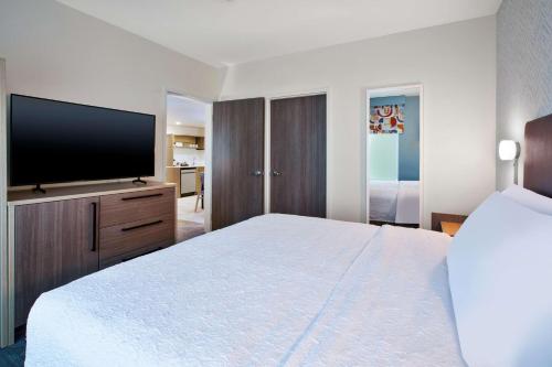 a hotel room with a bed and a flat screen tv at Home2 Suites By Hilton Grand Rapids Northeast in Grand Rapids
