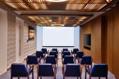 a conference room with chairs and a projection screen at Tumbi Hotel Dubai The Palm,Tapestry Collection Hilton in Dubai