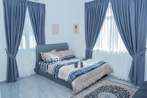 a bedroom with a bed with blue drapes at Anjung Teh Legacy in Jitra