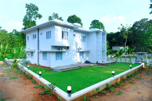 a white house with a lawn in front of it at Clubhouse pala in Lālam