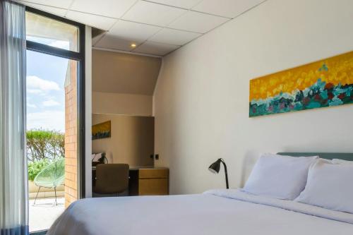 a bedroom with a bed and a desk and a window at Four Points by Sheraton Catania Hotel in Catania