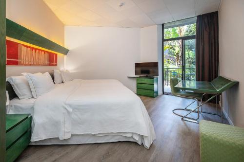 a bedroom with a bed and a desk and a window at Four Points by Sheraton Catania Hotel in Catania