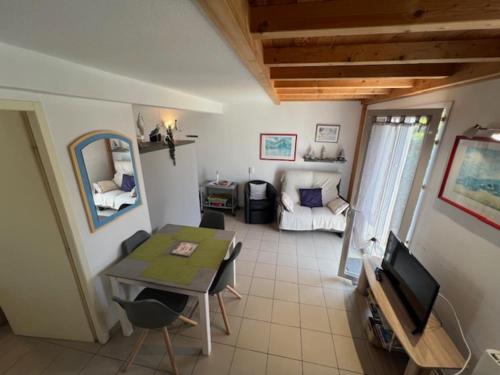 a living room with a table and a television at Maison lumineuse au calme, pres mer in Le Château-dʼOléron