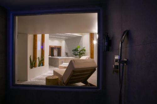 a mirror reflecting a bathroom with a chair and a tub at White Luxury in Thessaloniki