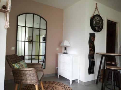 a living room with a mirror and a clock on the wall at Studio lumineux à 2 pas de la mer in Le Château-dʼOléron