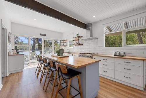 a kitchen with white cabinets and a counter with bar stools at Paradise Retreat Lakehouse - Jamieson - Sleeps 10 in Jamieson