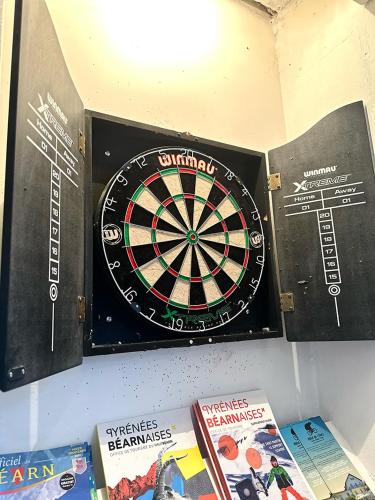 a dart board on a wall next to books at Hôtel de l'Ours in Arette