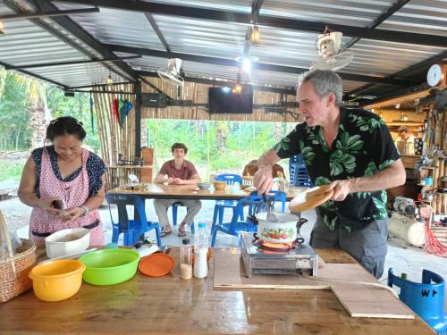 a man and a woman preparing food in a kitchen at Green Garden Homestay in Ban Khlong Waet