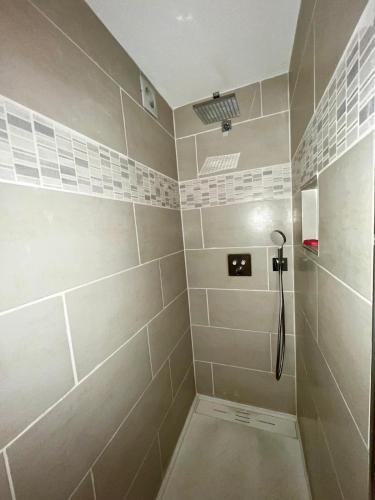 une salle de bain avec douche carrelée de blanc dans l'établissement Appartement Calme, à Morsbach