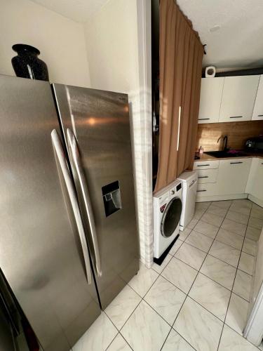 La cuisine est équipée d'un réfrigérateur en acier inoxydable, d'un lave-linge et d'un sèche-linge. dans l'établissement Appartement Calme, à Morsbach