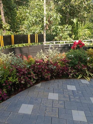 a garden with red flowers and a fence at Tea vista holiday home in Kalpetta