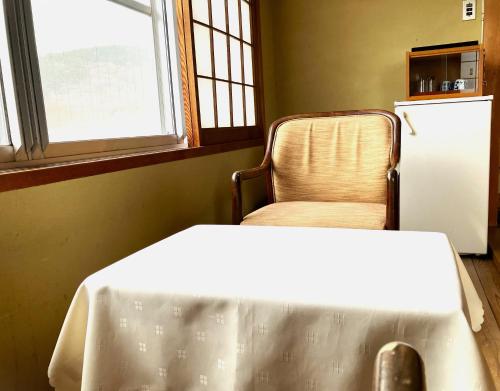 a room with a chair and a white table and a refrigerator at Chikurinin Gunpoen in Yoshino