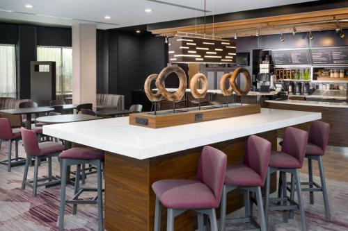 a bar in a restaurant with purple chairs at Courtyard by Marriott Buffalo Airport in Cheektowaga