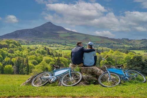 two people sitting on a rock next to two bikes at Powerscourt Hotel, Autograph Collection in Enniskerry