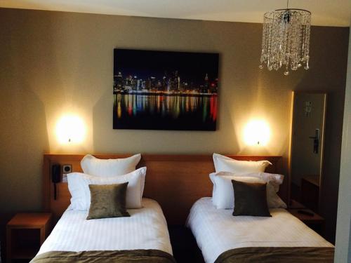 a hotel room with two beds and a painting on the wall at Hôtel Le Vouglans - Restaurant La Valouse in Orgelet