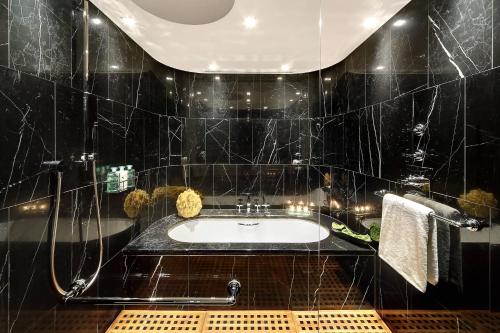 a black tiled bathroom with a sink and a shower at Bvlgari Hotel London in London