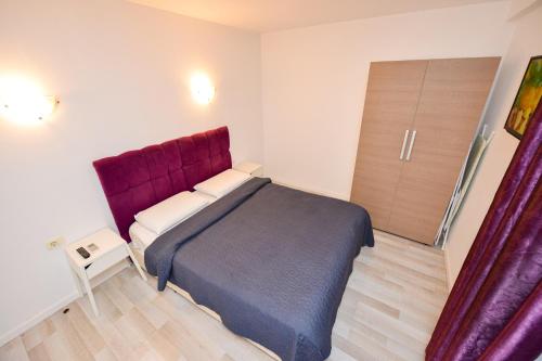 a bedroom with a bed with a purple headboard at Downtown Accommodation in Bucharest