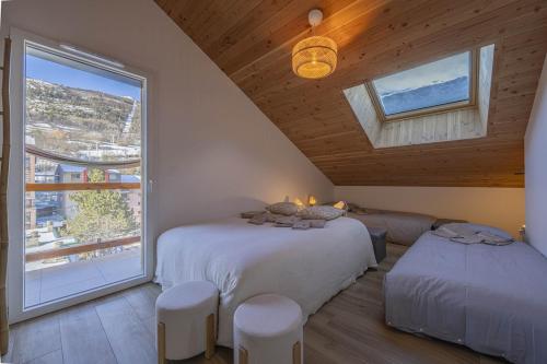 une chambre avec deux lits et une grande fenêtre dans l'établissement New T4 type chalet SerreChevalier face téléphérique, à Briançon