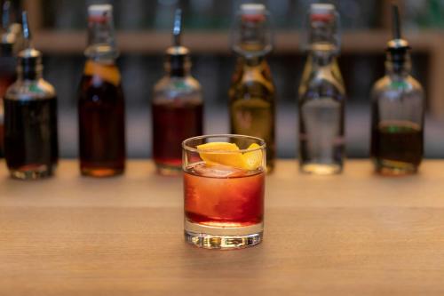 a drink with an orange slice in front of bottles at LUME Boutique Hotel, Autograph Collection in Frankfurt/Main