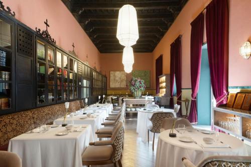 a dining room with white tables and chairs at Hotel Palacio de Santa Paula, Autograph Collection in Granada