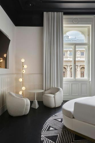 a bedroom with a bed and a chair and a window at W Budapest in Budapest