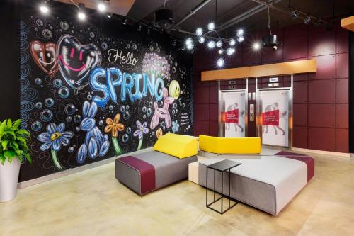 a room with a couch and a wall with a mural at Aloft Greenville Downtown in Greenville
