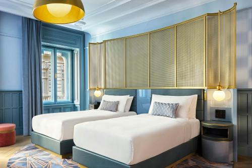 two beds in a room with blue walls and windows at W Budapest in Budapest