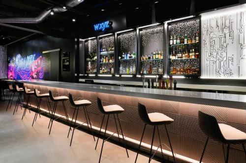a bar with a row of stools in a room at Aloft Greenville Downtown in Greenville