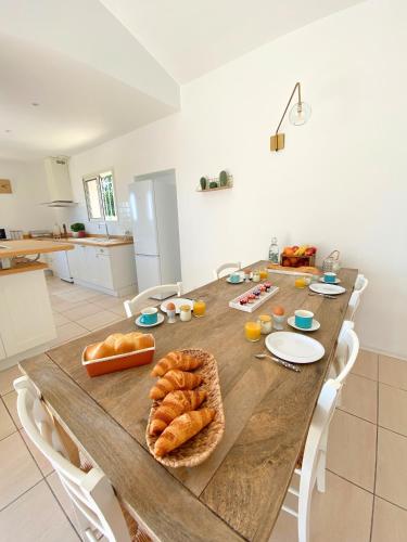 - une grande table en bois avec du pain dans la cuisine dans l'établissement Les Hauts de la Pinède - Villa avec Piscine, Jacuzzi et Boulodrome privatifs, à Thèzan-lès-Béziers