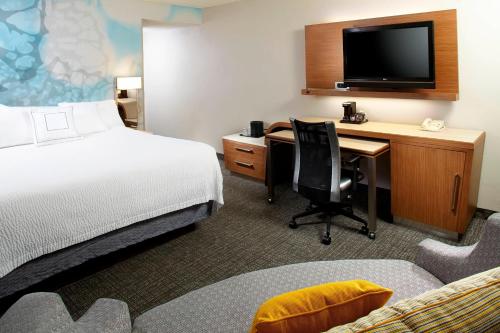 a hotel room with a bed and a desk with a computer at Courtyard by Marriott Lansing in Lansing