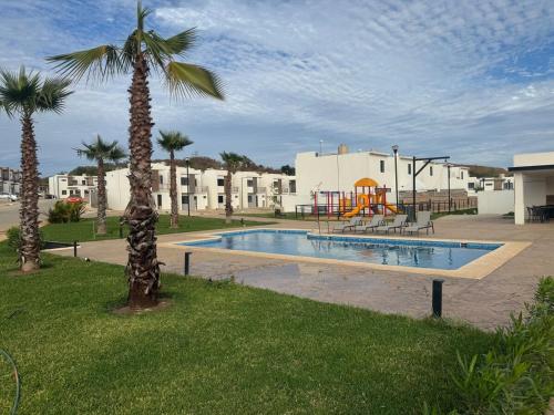 a swimming pool with a playground and a palm tree at Casa Ángeles in Mazatlán