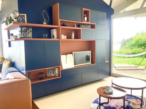 Elle comprend un salon doté d'un mur bleu et d'une télévision. dans l'établissement Exclusivité Villa d'Exception en Bord de Mer, à Saint-Cast-le-Guildo