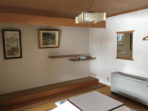 Habitación con mesa y espejo en la pared. en Tsugaike Ski House en Otari