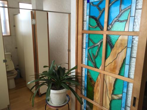 baño con una puerta de vidriera con una maceta en Tsugaike Ski House en Otari