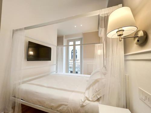 a white bedroom with a bed and a window at Dimore della Cisterna in Stresa