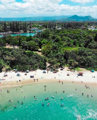 an aerial view of a beach with people in the water at 1980s Coastal Escape in Brunswick Heads in Brunswick Heads