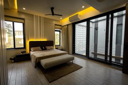 a bedroom with a bed and large windows at Aviran Villa 5BHK - Jacuzzi House in Lonavala