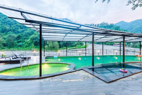 a large swimming pool with a metal canopy at DLS Divine River Resort and Spa, Rishikesh in Rishīkesh