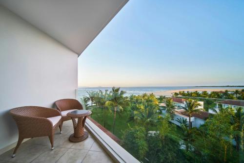 a room with a balcony with a view of the ocean at Renaissance Danang Hoi An Resort & Spa in Hoi An