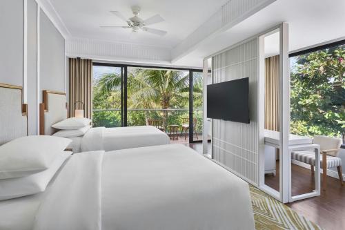 a white bedroom with two beds and a flat screen tv at Renaissance Danang Hoi An Resort & Spa in Hoi An