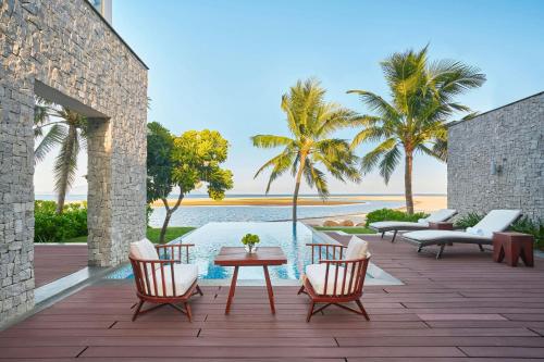 a patio with chairs and a table next to a pool at Renaissance Danang Hoi An Resort & Spa in Hoi An