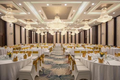 a large banquet hall with white tables and yellow chairs at Renaissance Danang Hoi An Resort & Spa in Hoi An