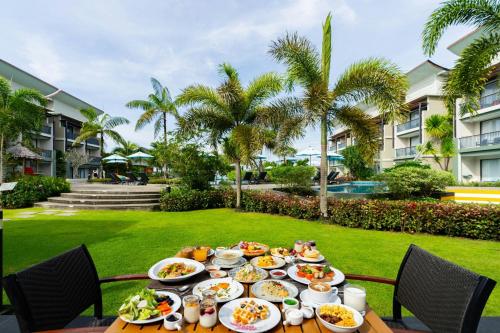 een tafel met eten in een tuin met palmbomen bij Le Meridien Khao Lak Resort & Spa in Khao Lak