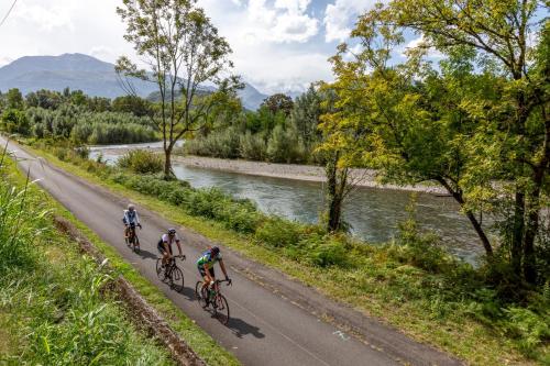 three people riding bikes down a road next to a river at Hôtel Roissy in Lourdes
