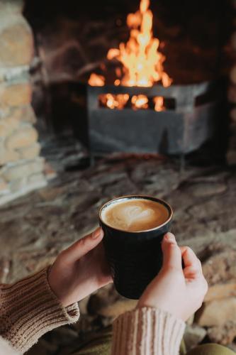 a person holding a cup of coffee in front of a fireplace at Nambiti Plains Lodge in Nambiti Private Game Reserve