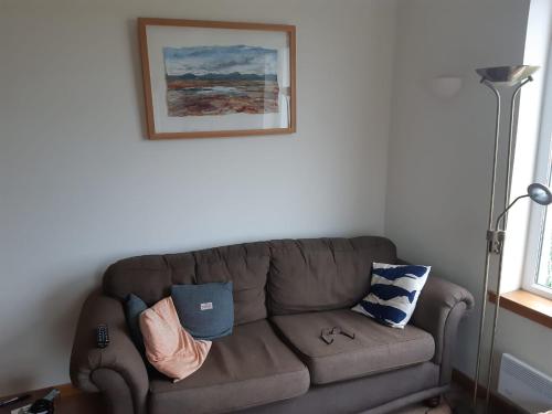 a living room with a brown couch with pillows at Taigh Nandag in Valtos