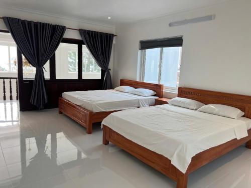 twee bedden in een kamer met ramen bij Biệt Thự Nguyên Căn đường Trần Phú Vũng Tàu - View Biển Bãi trước - Hồ bơi sân vườn riêng - 7 phòng ngủ lớn in Vung Tau