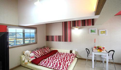 a bedroom with a bed with red and white sheets and a table at Bluesean Pension in Namhae