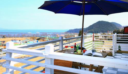 a table with an umbrella on top of a balcony at Bluesean Pension in Namhae