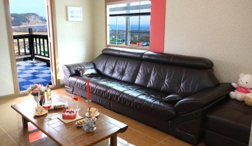 a living room with a leather couch and a table at Bluesean Pension in Namhae